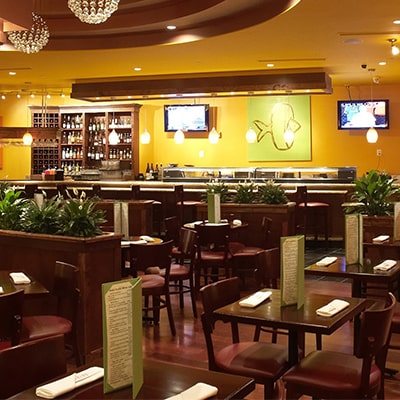 A spacious restaurant featuring neatly arranged tables and chairs in the center, inviting guests to dine comfortably.
              