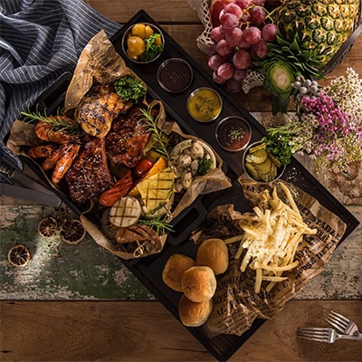 A tray filled with various dishes placed on a rustic wooden table, showcasing a delightful array of food.