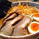  A bowl of ramen featuring tender meat slices and soft-boiled eggs, garnished with green onions and broth.