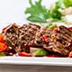  A beautifully plated steak accompanied by vibrant vegetables and a rich sauce on a pristine white plate.
