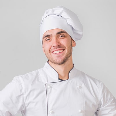 A smiling man wearing a chef's uniform, exuding warmth and professionalism in a culinary setting.